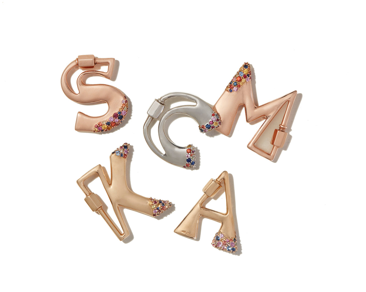 Gold locks of every letter of the alphabet including A charm against white backdrop with Marla Aaron logo in bottom left corner