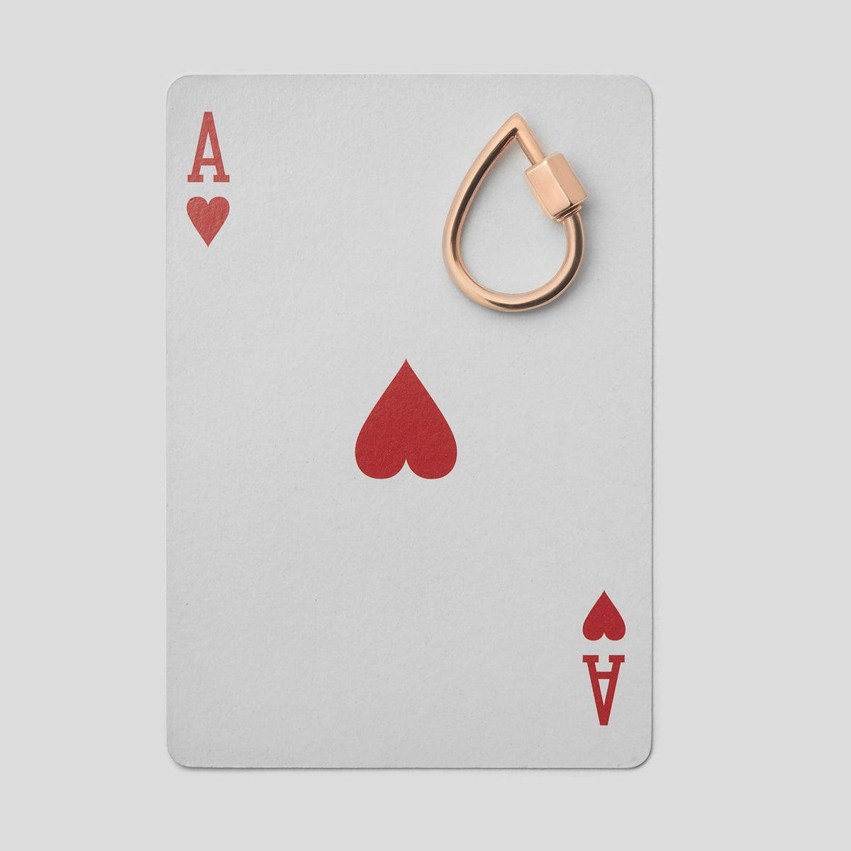 Small rose gold droplock on top of ace of hearts playing card