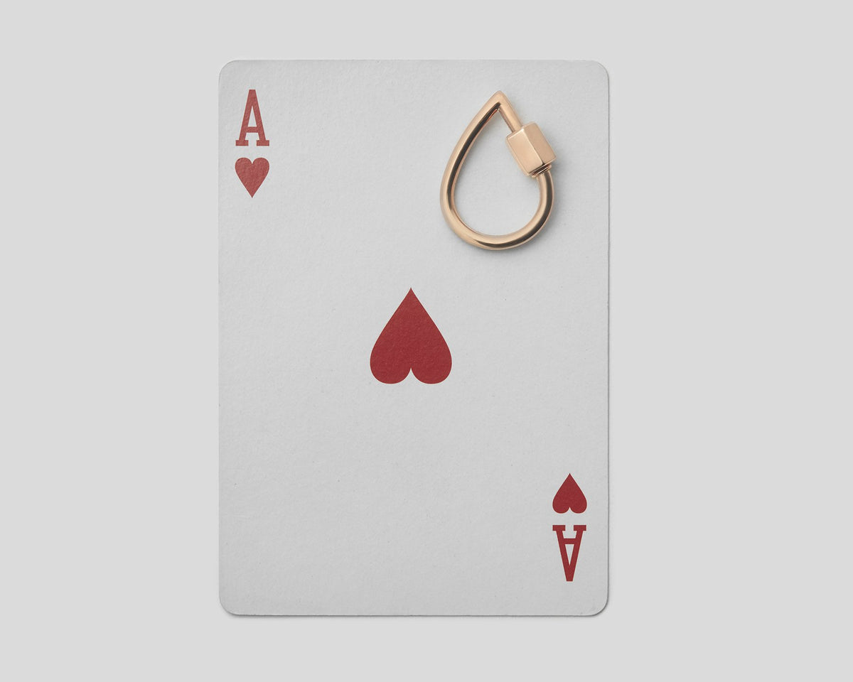 Small rose gold droplock on top of ace of hearts playing card