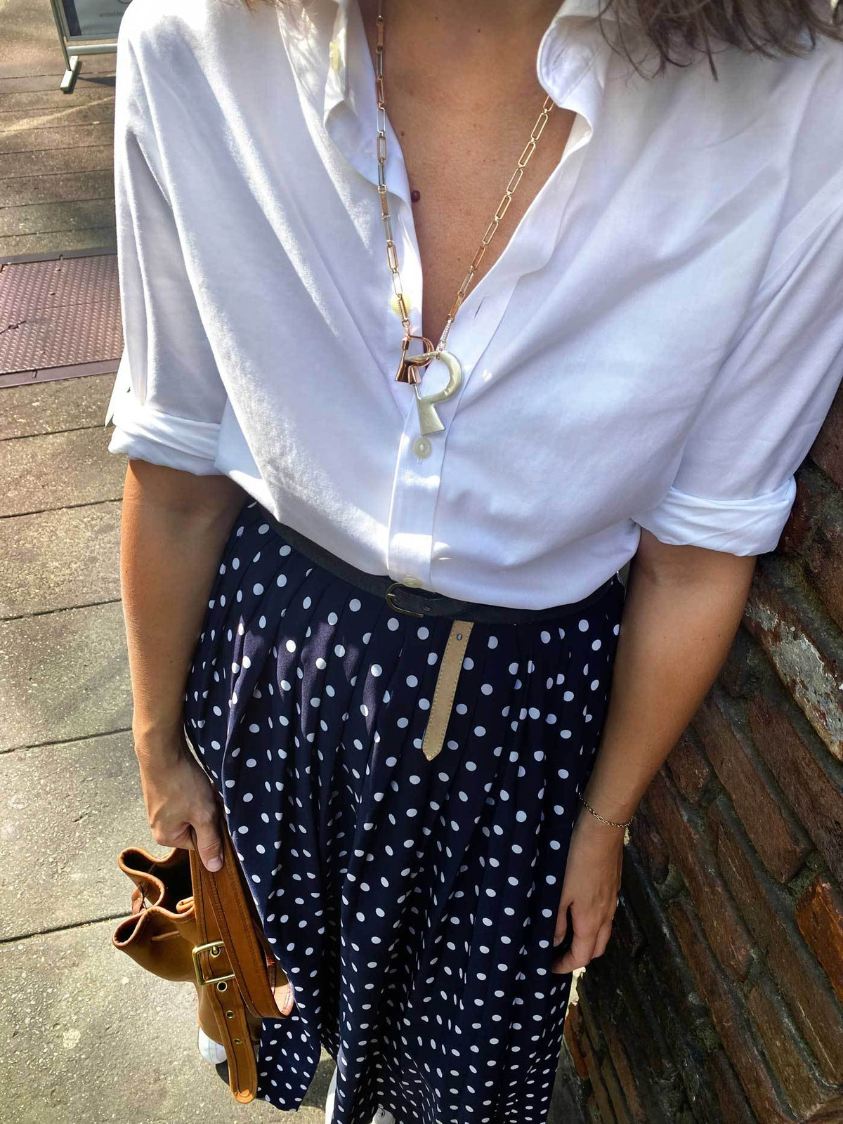 Close up of woman's decolletage wearing necklace with P lock
